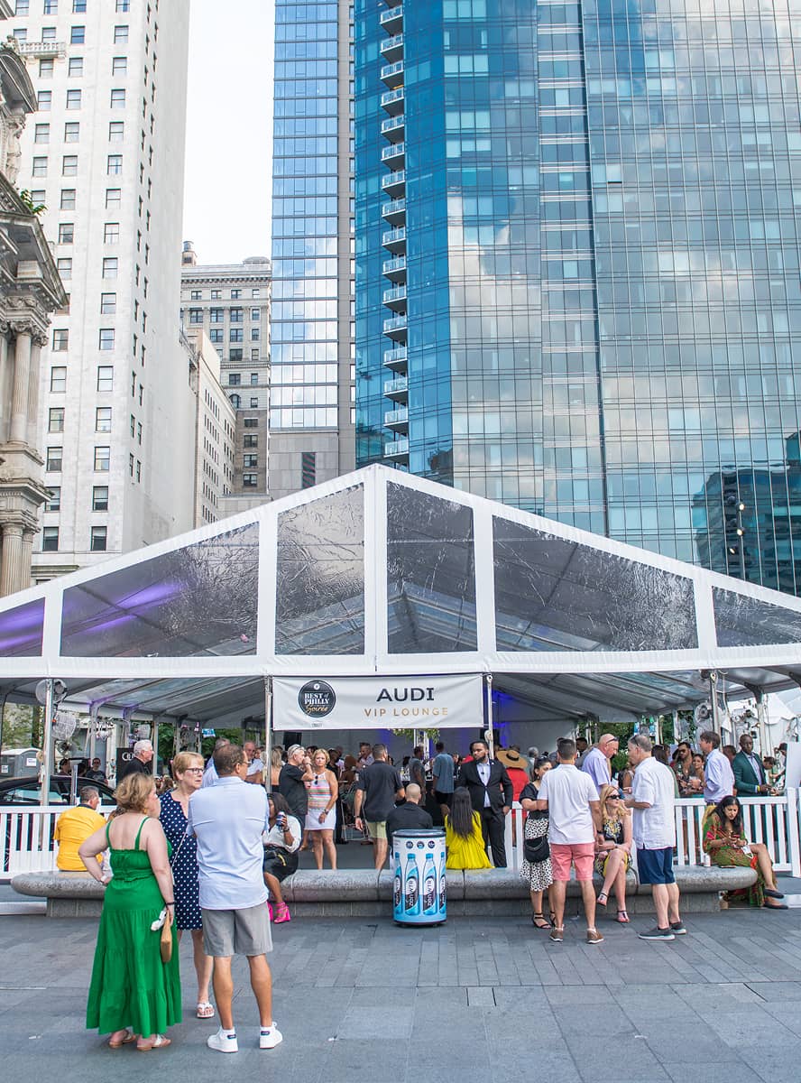 Crowd gathered in front of a white, transparent tent labeled 