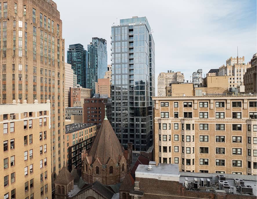 View of a cityscape featuring diverse architectural styles. A modern glass building contrasts with old brick structures, creating a dynamic city vibe.