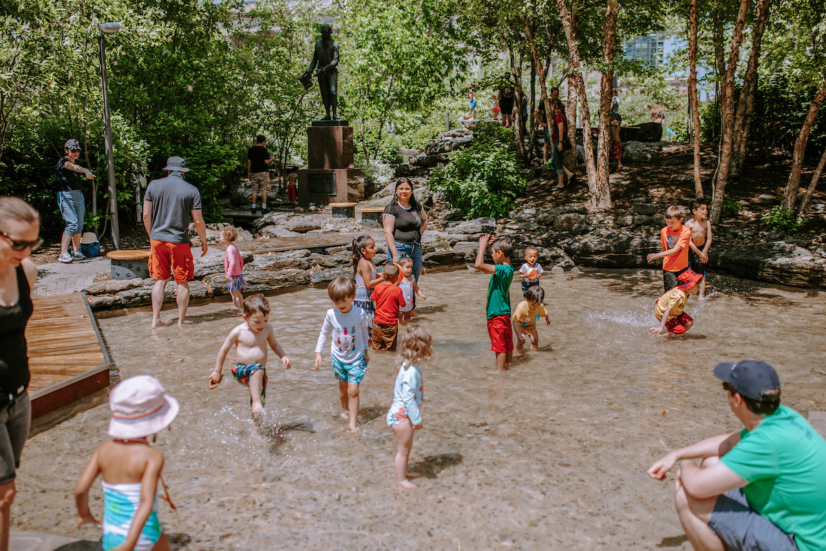 Children and parents playing in pond and playground.